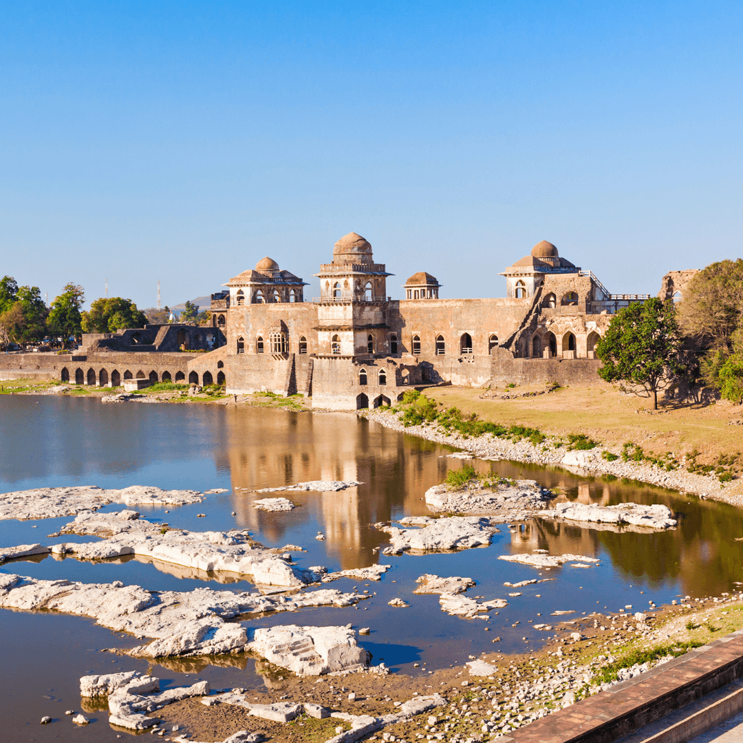 Explore the enigmatic Jahaz Mahal in Mandu, set amidst lush landscapes and reflective ponds, symbolizing the rich architectural heritage of the region.