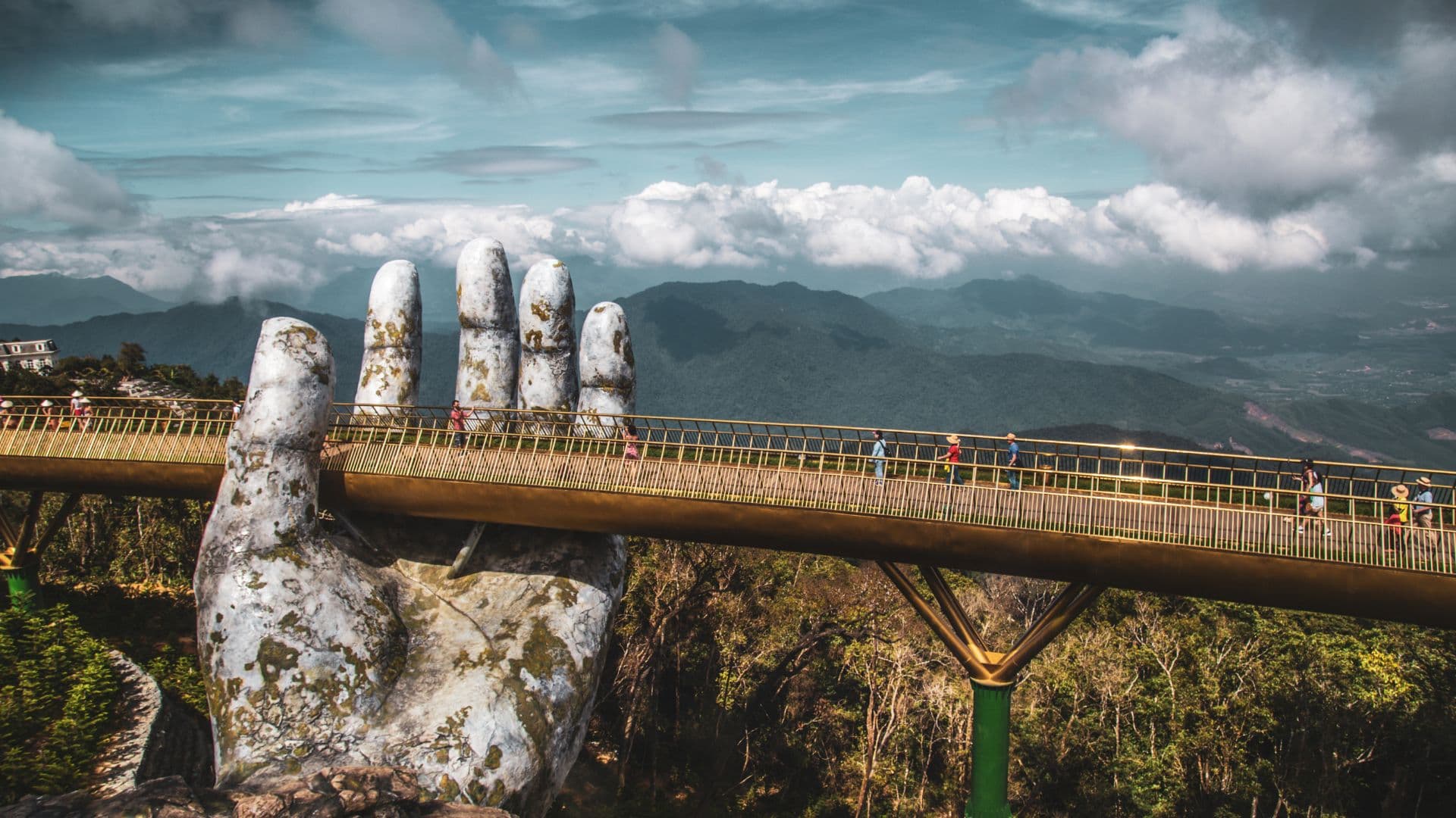 ChatGPT said: The Golden Bridge gracefully stretches across the mountains of Ba Na Hills, held by giant stone hands and surrounded by panoramic views of lush, misty peaks.